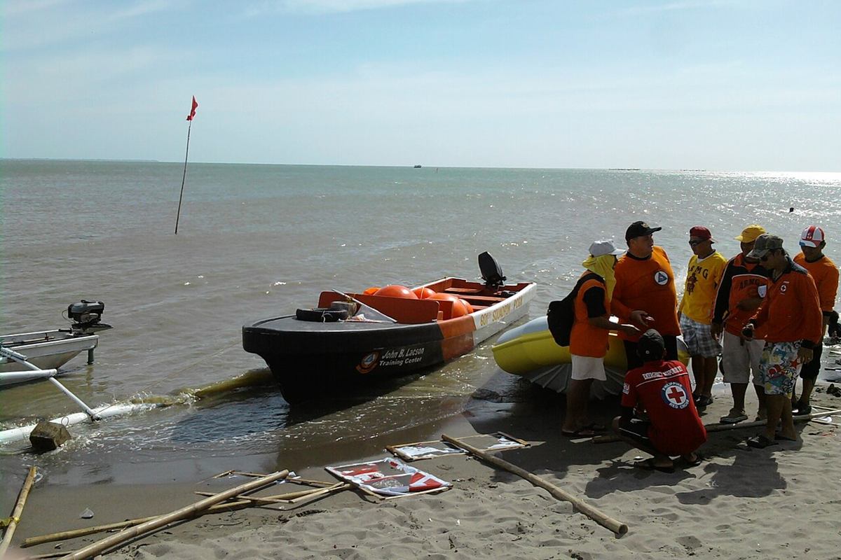 Philippine Coast Guard Auxiliary volunteers and a rescue boat on a beach in Iloilo City.