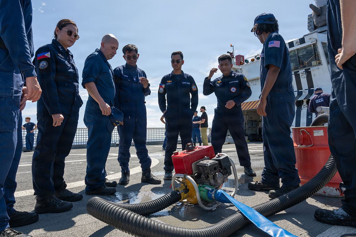 Philippine Coast Guard members receiving damage-control pump training on a ship's flight deck.